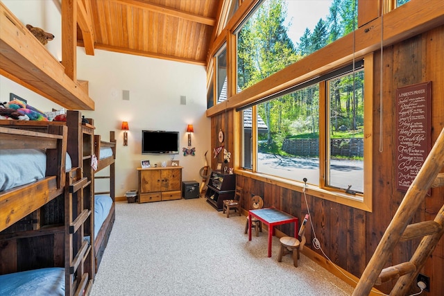 living room with wooden walls, beam ceiling, wood ceiling, carpet, and high vaulted ceiling