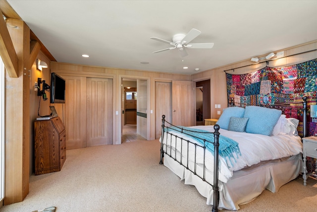 bedroom featuring wooden walls, ceiling fan, and light colored carpet