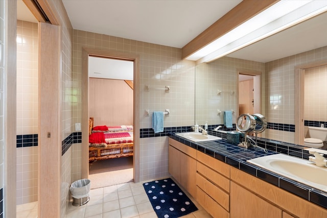 bathroom featuring dual vanity, tile flooring, toilet, and tile walls