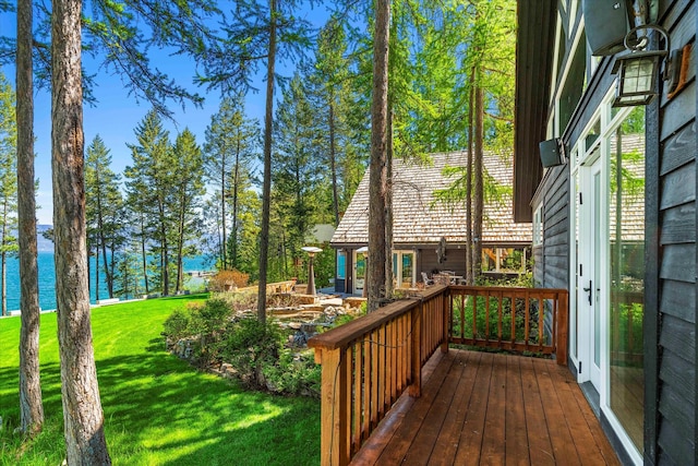 deck with a water view and a lawn