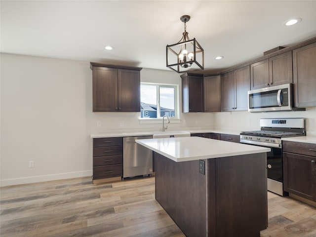 kitchen featuring appliances with stainless steel finishes, dark brown cabinetry, light hardwood / wood-style floors, and an inviting chandelier