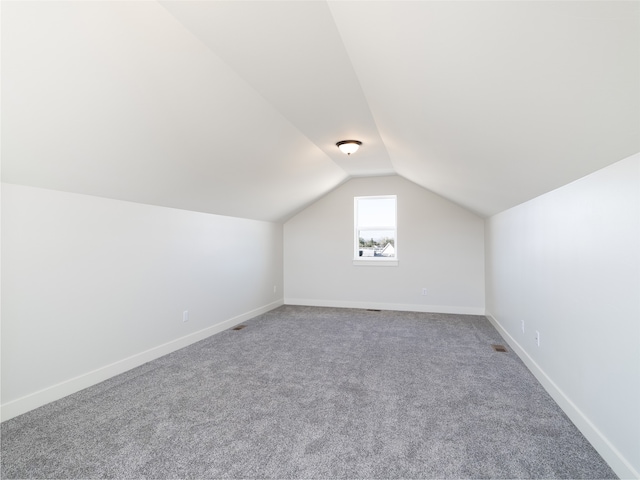 bonus room with vaulted ceiling and carpet flooring