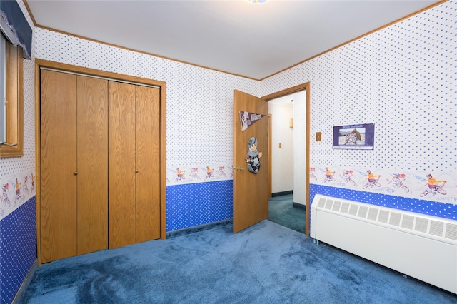 bedroom with dark colored carpet, ornamental molding, radiator, and a closet