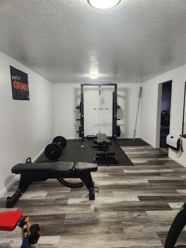 exercise area with dark hardwood / wood-style flooring and a textured ceiling