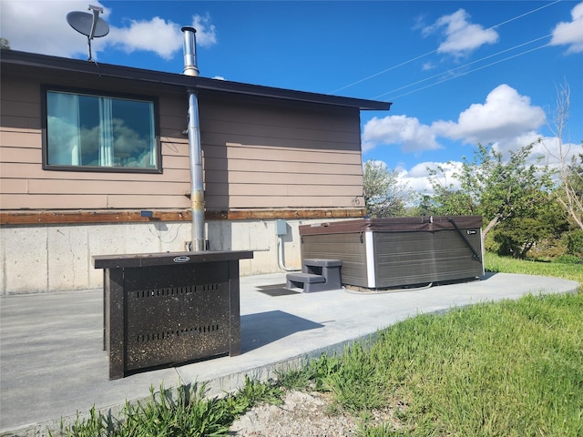 view of property exterior featuring a patio and a hot tub