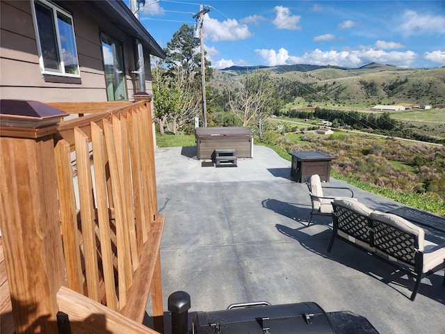 view of patio featuring a mountain view, outdoor lounge area, and a hot tub