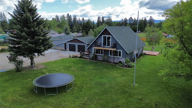 exterior space with a balcony, a garage, a trampoline, and a yard