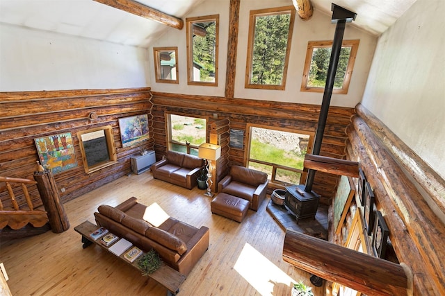 living room with vaulted ceiling with beams, light hardwood / wood-style floors, and a wood stove