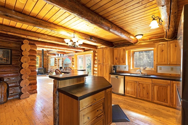 kitchen with a chandelier, a wood stove, a healthy amount of sunlight, and stainless steel dishwasher