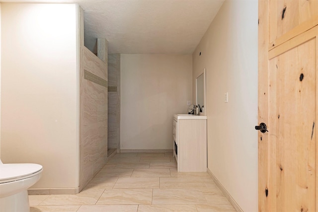 bathroom with a textured ceiling, toilet, and sink