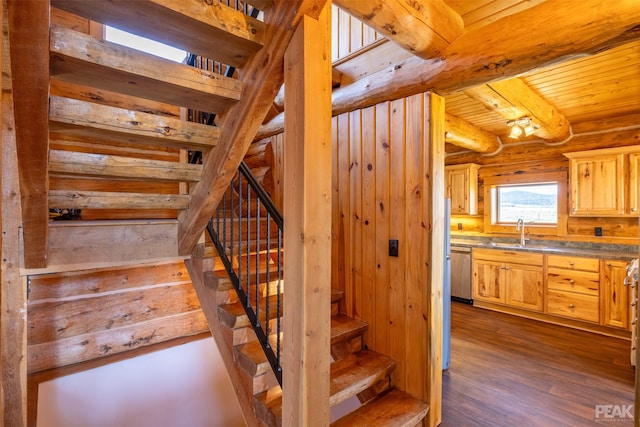 stairway with rustic walls, wood ceiling, sink, hardwood / wood-style flooring, and beamed ceiling