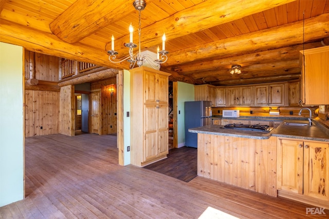 kitchen featuring beam ceiling, dark hardwood / wood-style floors, decorative light fixtures, and stainless steel appliances