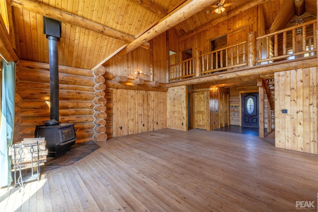 unfurnished living room featuring a wood stove, high vaulted ceiling, ceiling fan, wood-type flooring, and wood ceiling