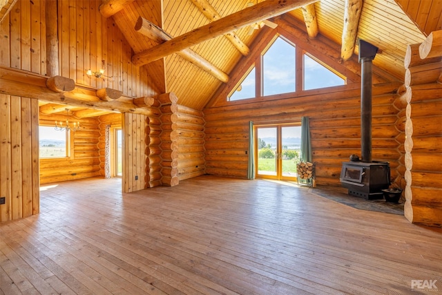 unfurnished living room with beamed ceiling, high vaulted ceiling, a wood stove, and hardwood / wood-style flooring