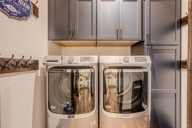 clothes washing area with separate washer and dryer and cabinets