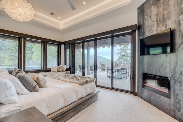 carpeted bedroom with access to exterior, a fireplace, and a chandelier