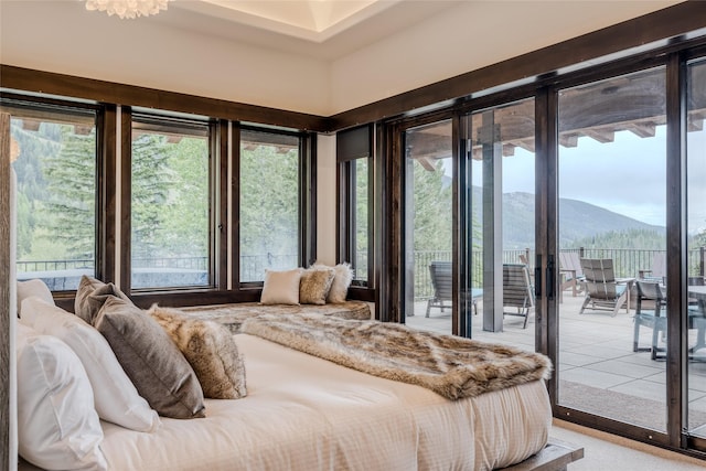 bedroom with a mountain view, multiple windows, and access to outside