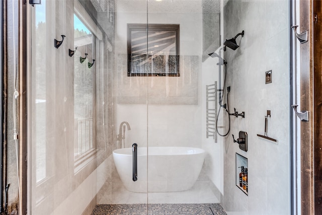 bathroom with shower with separate bathtub and tile walls