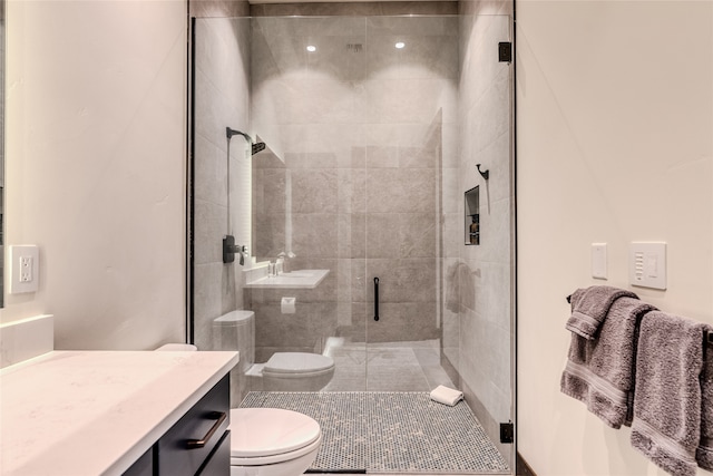 bathroom with a shower with shower door, toilet, and vanity