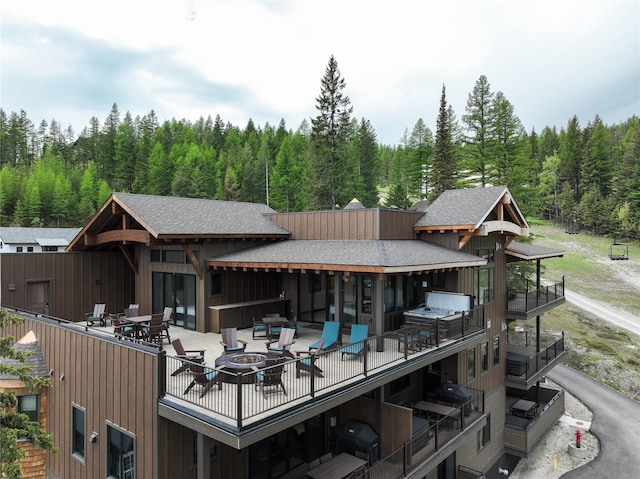 back of property with an outdoor fire pit, a balcony, and a patio