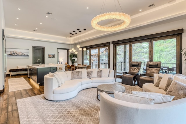 living room with dark hardwood / wood-style flooring, a tray ceiling, and sink