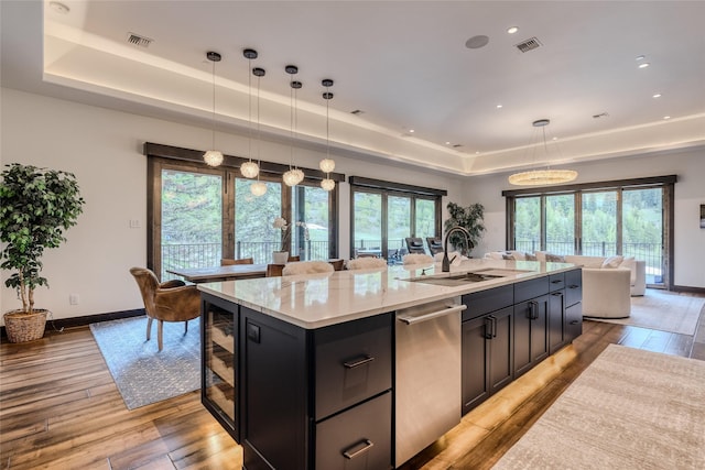 kitchen featuring hanging light fixtures, stainless steel dishwasher, a tray ceiling, and sink