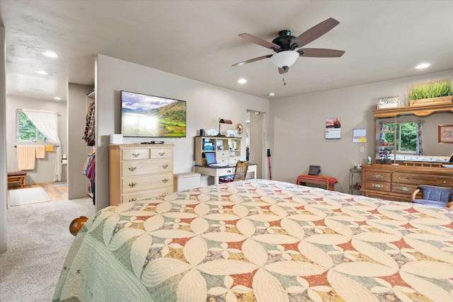 carpeted bedroom featuring multiple windows, ceiling fan, and ensuite bath