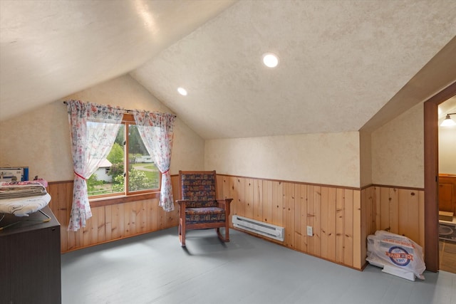 living area with a textured ceiling, a baseboard radiator, vaulted ceiling, and wood walls