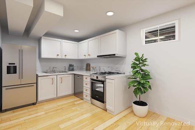 kitchen featuring appliances with stainless steel finishes, light hardwood / wood-style flooring, white cabinetry, and sink