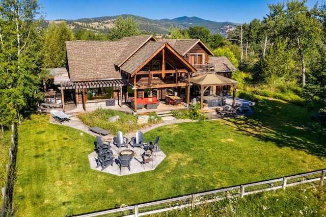 back of house featuring a patio, a yard, a mountain view, and a fire pit