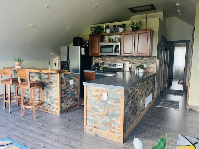 kitchen with appliances with stainless steel finishes, lofted ceiling, light hardwood / wood-style flooring, and tasteful backsplash