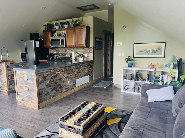 kitchen featuring appliances with stainless steel finishes, backsplash, wood-type flooring, sink, and vaulted ceiling