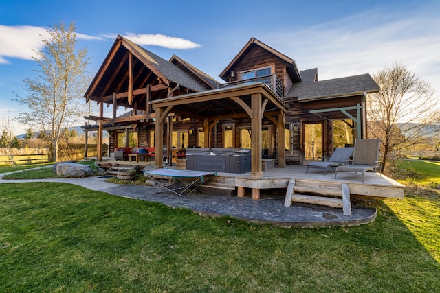 rear view of property featuring a lawn, a hot tub, and a wooden deck