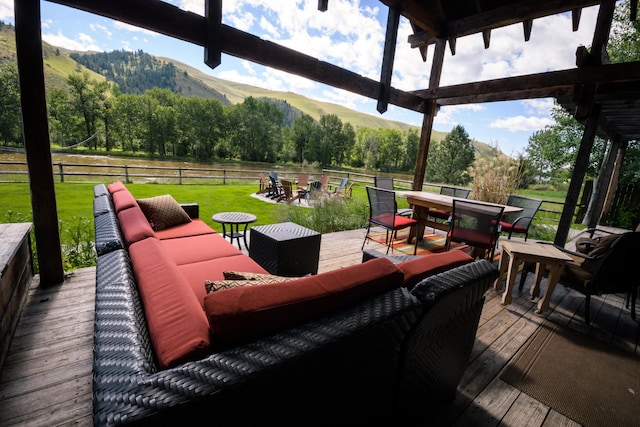 wooden terrace with an outdoor living space, a mountain view, and a yard