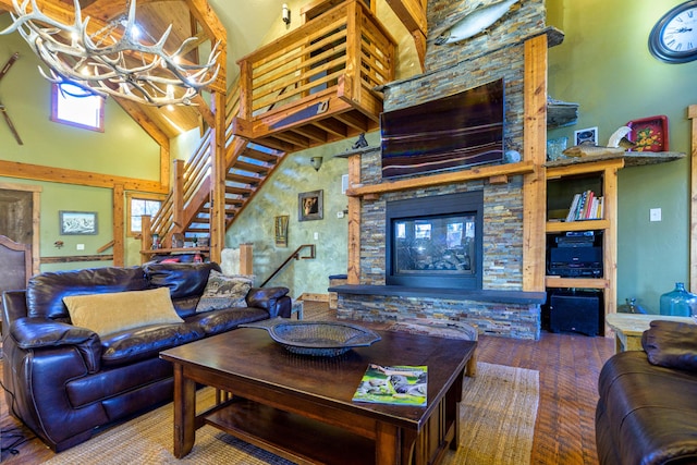 living room with an inviting chandelier, a towering ceiling, and a stone fireplace