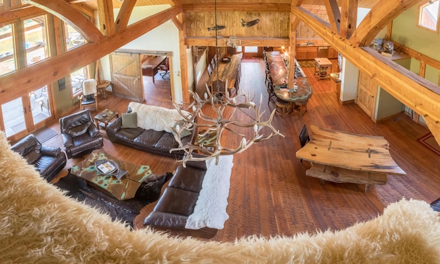 living room featuring beam ceiling, high vaulted ceiling, hardwood / wood-style flooring, and wooden walls