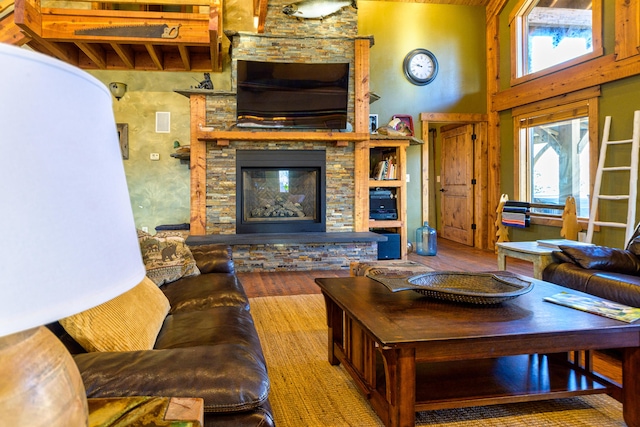 living room with a towering ceiling, a fireplace, and hardwood / wood-style floors