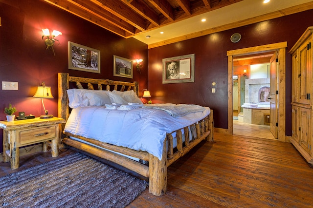 bedroom with beamed ceiling, dark hardwood / wood-style floors, and connected bathroom