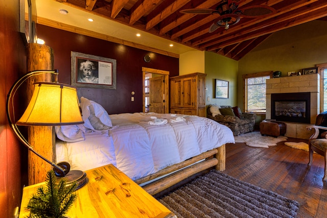 bedroom with beamed ceiling, a tiled fireplace, and dark hardwood / wood-style flooring