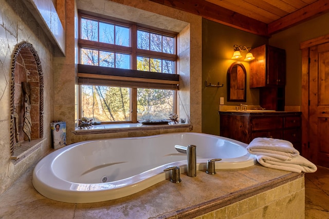 bathroom with a healthy amount of sunlight, tiled bath, vanity, and wood ceiling