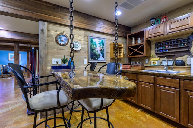 interior space featuring a kitchen breakfast bar, sink, and wooden walls