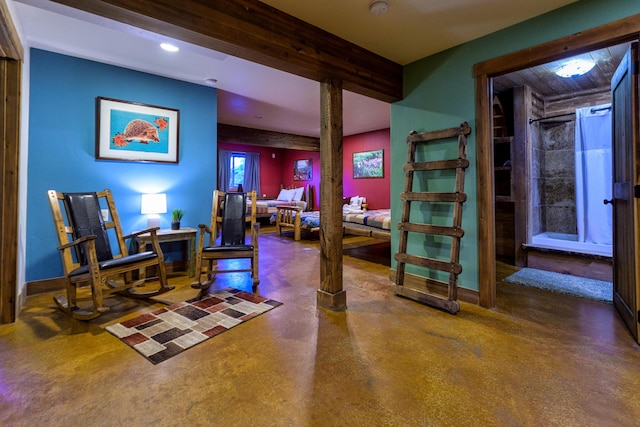 sitting room featuring beamed ceiling and concrete flooring