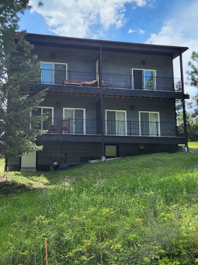 back of property featuring a lawn and a balcony