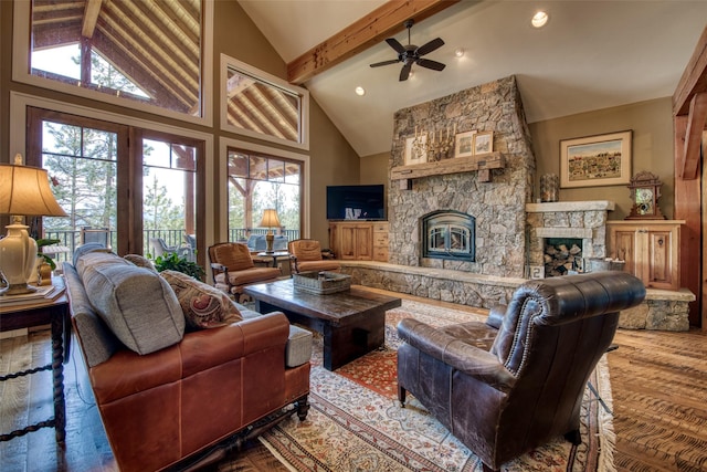 living room with ceiling fan, beam ceiling, high vaulted ceiling, wood-type flooring, and a stone fireplace