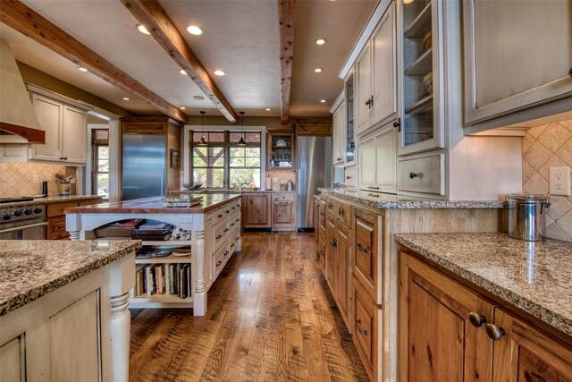 kitchen with high quality appliances, light stone countertops, dark wood-type flooring, and beamed ceiling