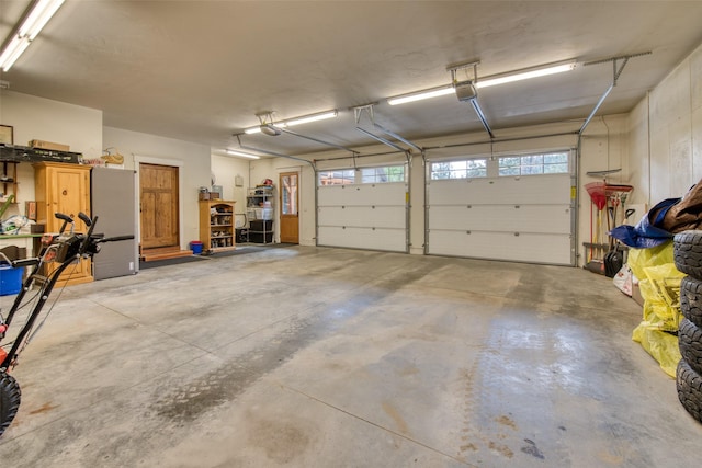 garage featuring a garage door opener and stainless steel fridge