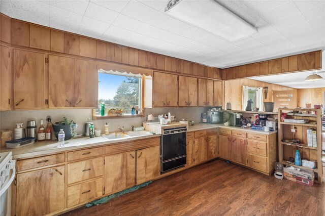 kitchen with dishwasher, dark wood-type flooring, white range, sink, and wooden walls