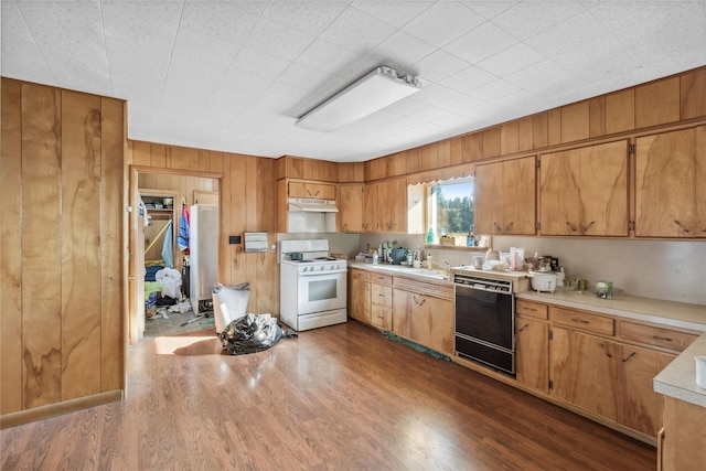 kitchen with white gas range, wooden walls, dark hardwood / wood-style flooring, and black dishwasher