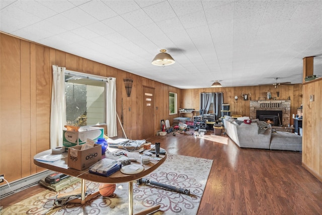 living room featuring a fireplace, wooden walls, dark hardwood / wood-style flooring, and a baseboard heating unit