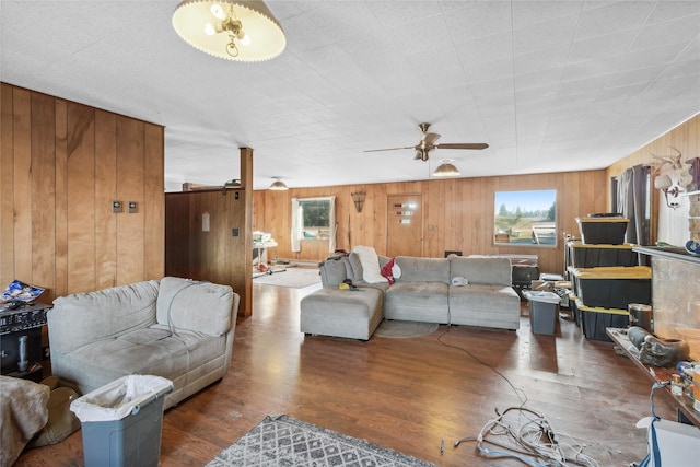 living room featuring ceiling fan, dark hardwood / wood-style flooring, and wooden walls